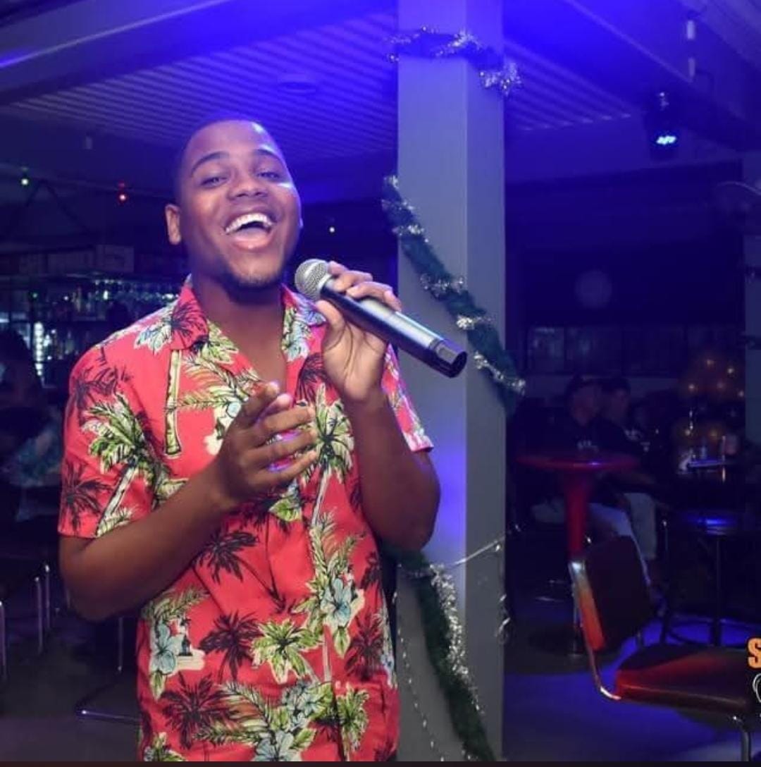Quin Biekman singing into a microphone on stage in Paramaribo
